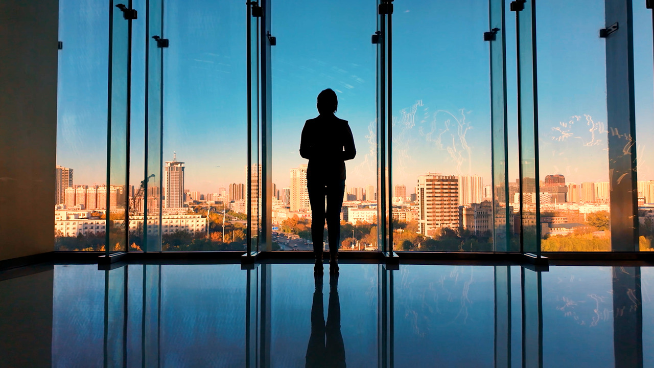 A person standing in a building looking out over a city.