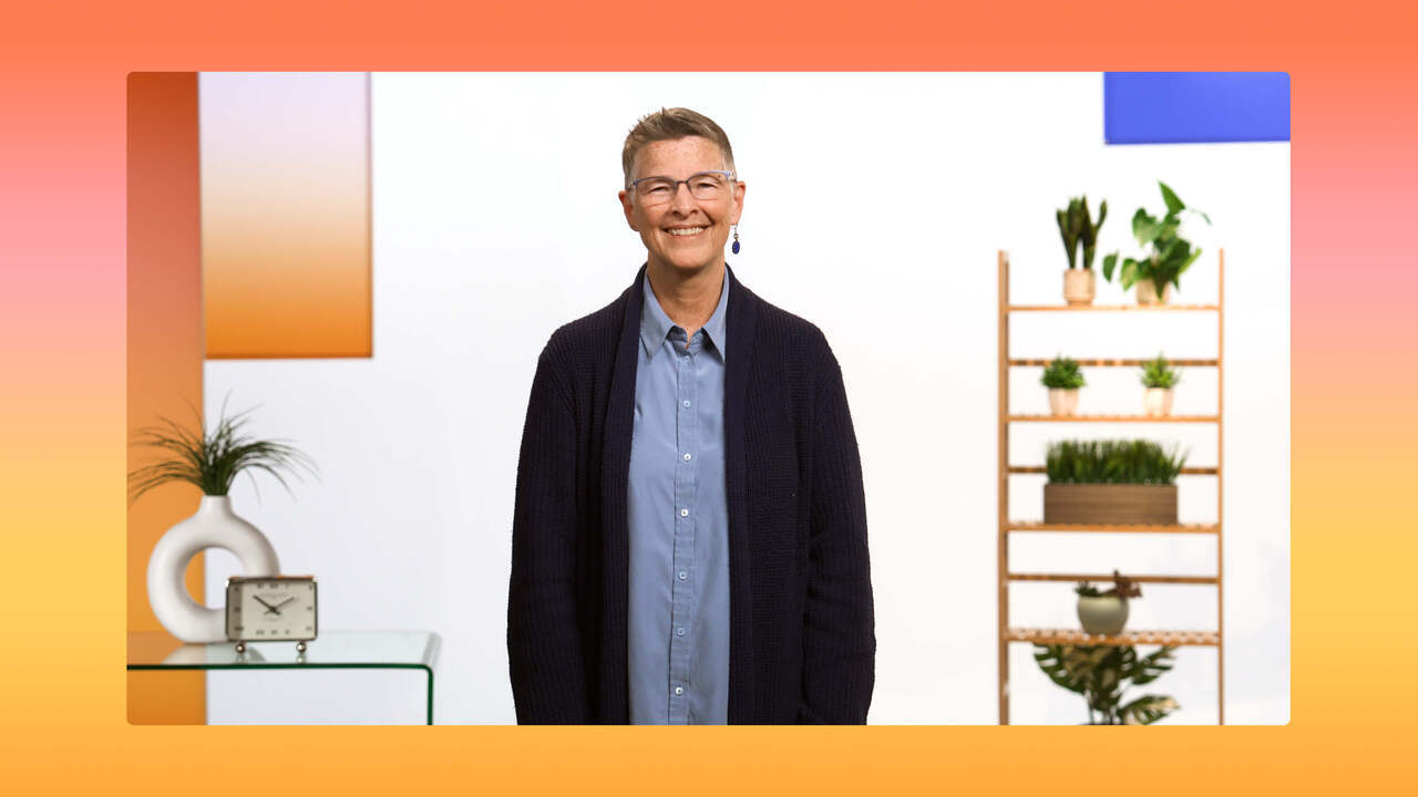 A smiling Tammy Snow stands in a bright, modern office setting with a play button overlay. They wear a blue button-down shirt and a navy cardigan, set against a vibrant orange and yellow gradient border.