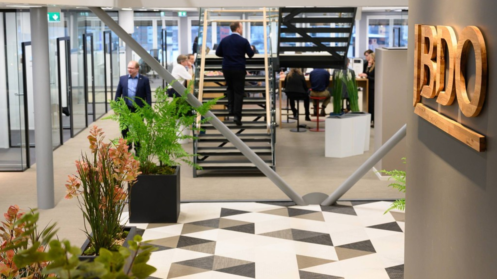 Image of a man walking up the steps  with people sitting at a table behind the steps.