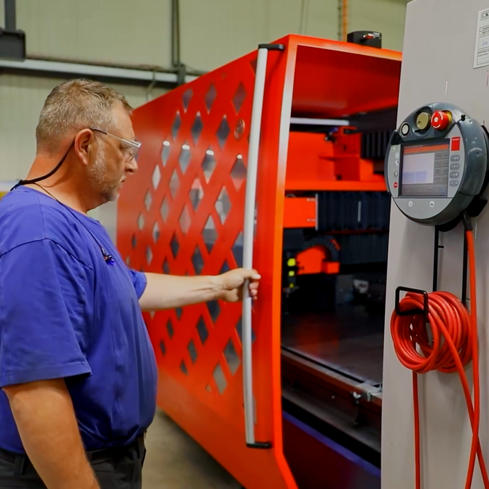 An older male employee wearing a blue shirt and safety glasses.