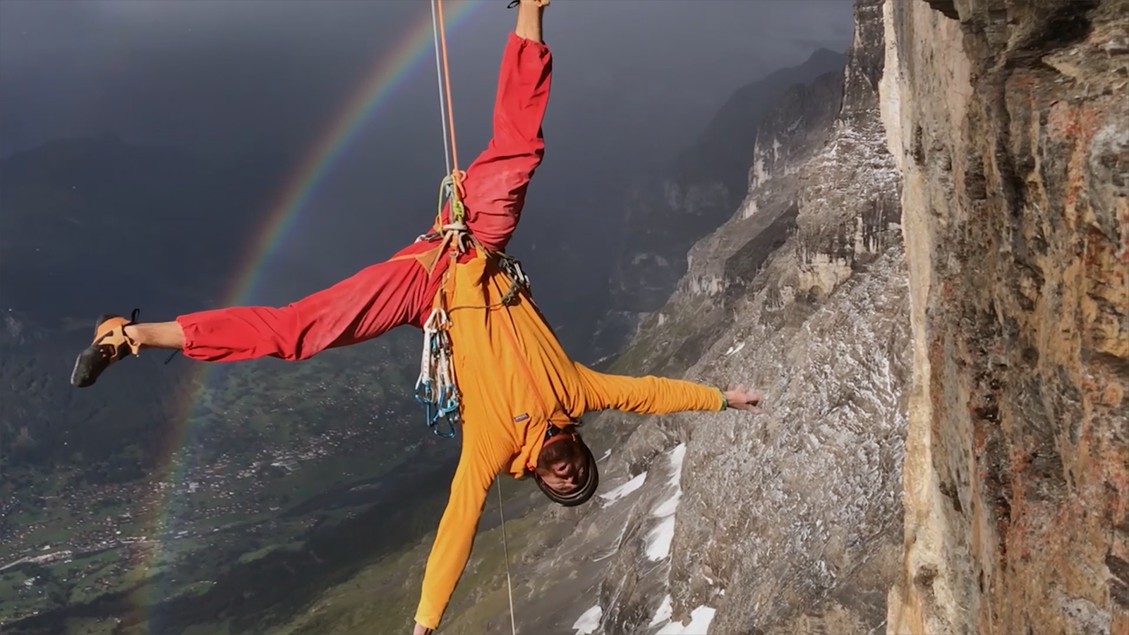 Image of a rock climber with a rainbow beyond them